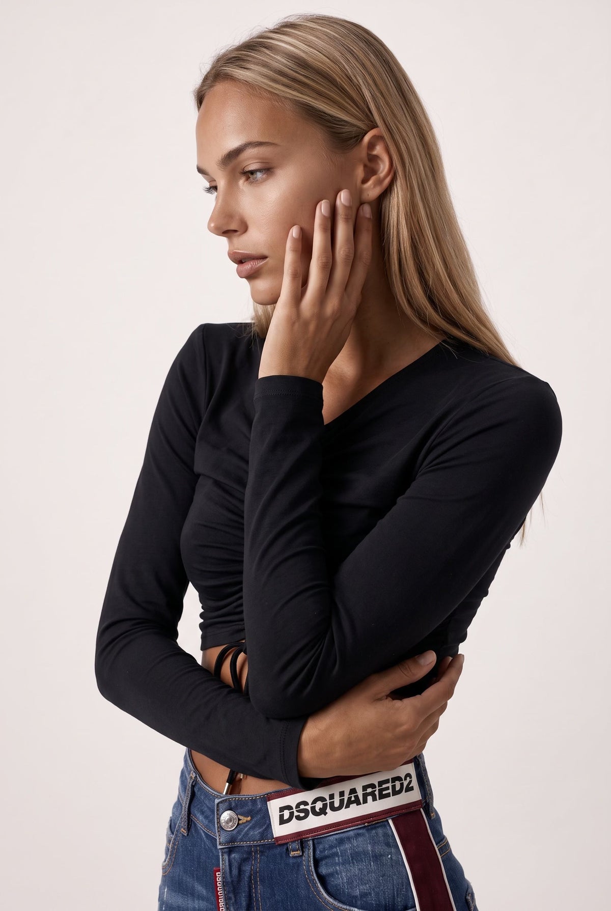 The Saint 54 black long-sleeve crop top with shoulder pads, adjustable front ties, and gold-tone tips on a model.