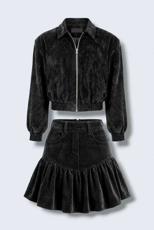 The Saint 54 black suede bomber jacket and ruffled mini skirt set worn by a model against a white background.