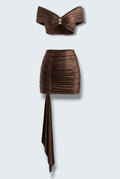 The Saint 54 brown two-piece set featuring a cropped draped top with gold detail and a ruched mini skirt with a scarf.