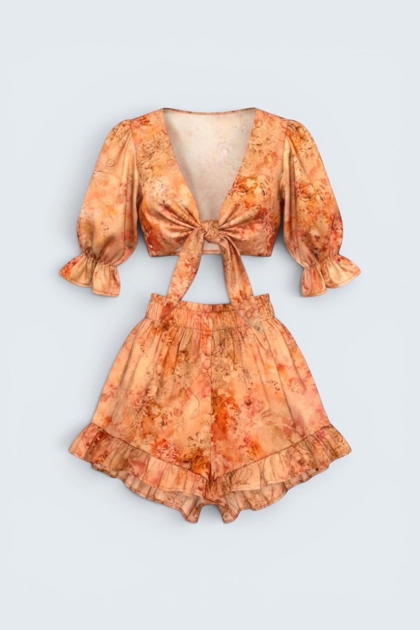 The Saint 54 sunset floral print two-piece set with tie-front puff sleeve top and high-waisted ruffled mini shorts.